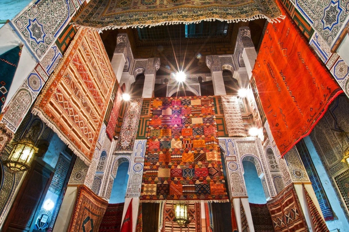 Colorful traditional Moroccan rugs hung inside historical architecture in Fès, Morocco.
