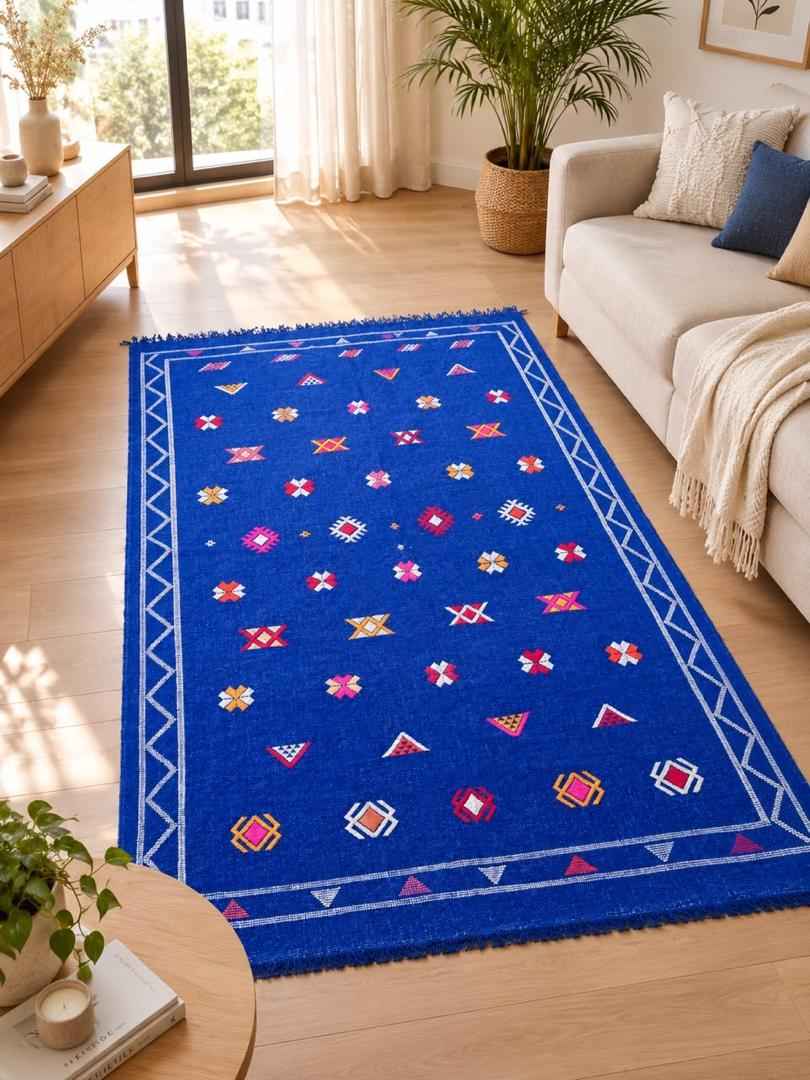 Tapis marocain bleu aux motifs géométriques multicolores, posé au pied d'un lit